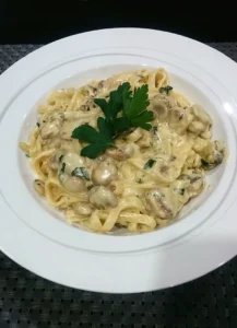 A bowl of super creamy fettucine alfredo with mushrooms and garnished with parsley