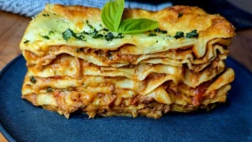 A slice of delicious lasagne, showing layers of pasta, ragu and cheese